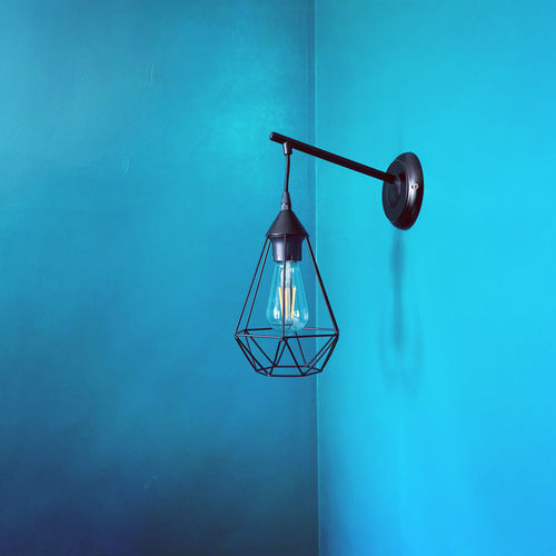 Close-up of illuminated light bulb against blue wall