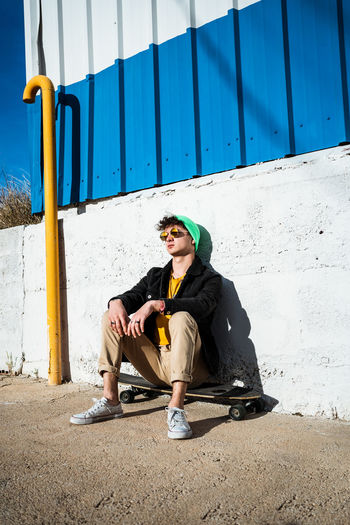 Full length of young man sitting on wall