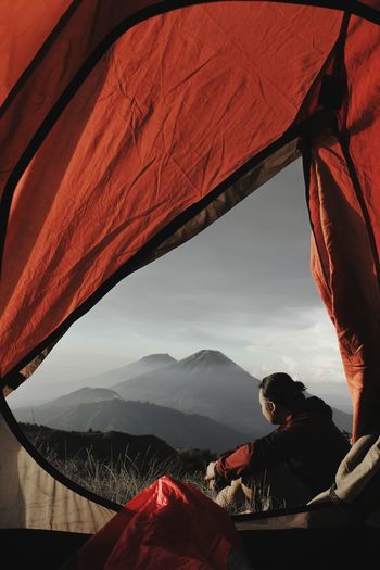 PEOPLE SITTING BY MOUNTAINS AGAINST SKY
