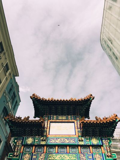 Low angle view of shrine amidst buildings against sky