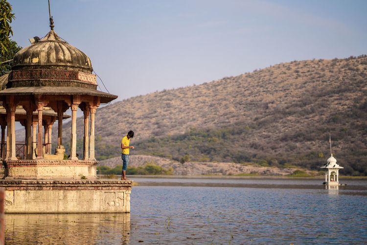 Man standing at temple over lake
