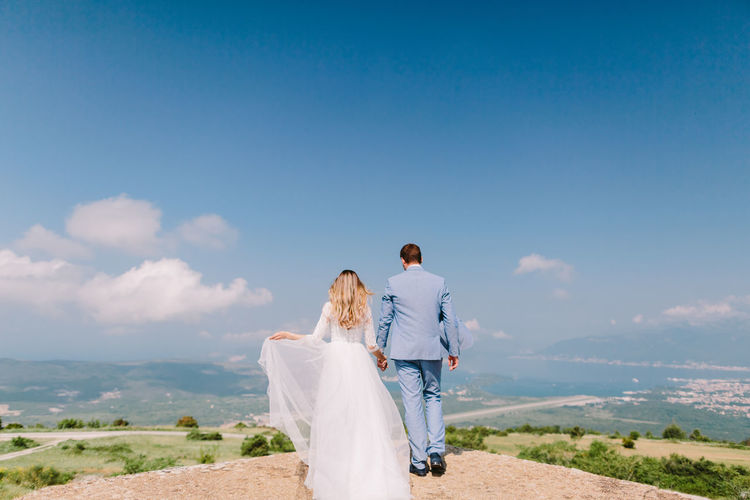 Rear view of married couple standing at observation point against sky
