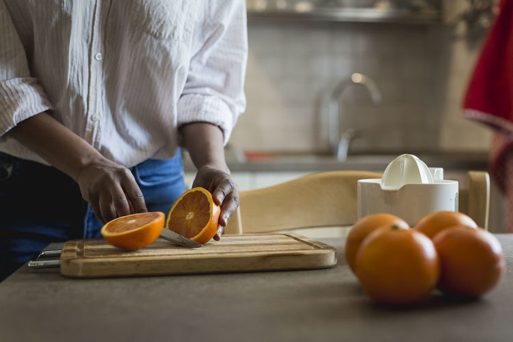 Midsection of man standing on cutting board at home