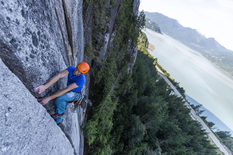 Man lead climbing granite squamish with background view of ocean