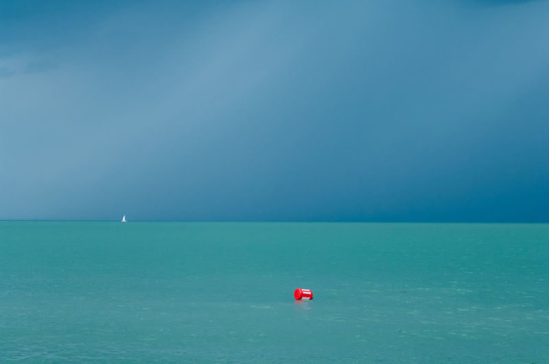 Red floating on sea against blue sky