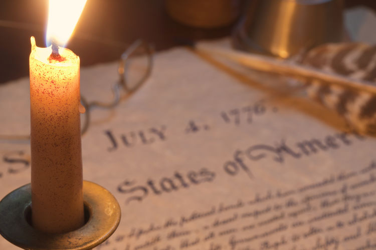Lit candle on declaration of independence at table