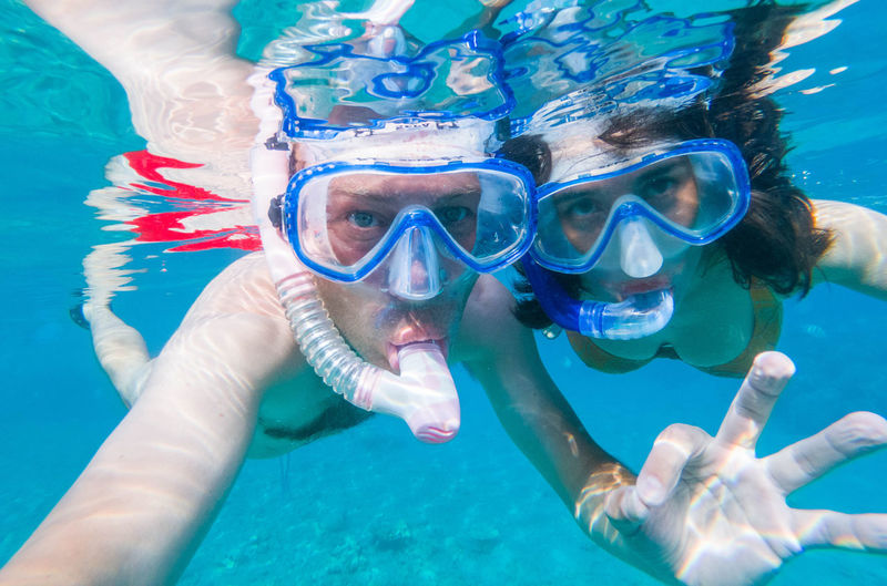 Couple using snorkels while swimming undersea