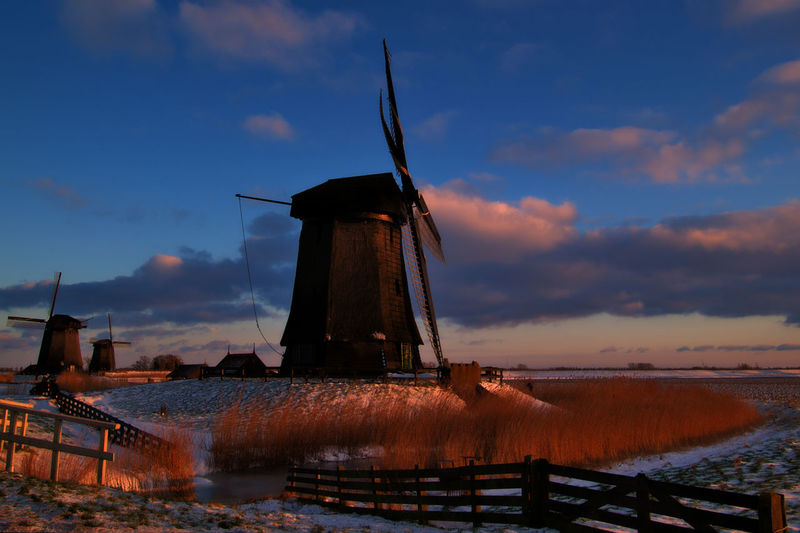 Traditional windmill against sky at sunset
