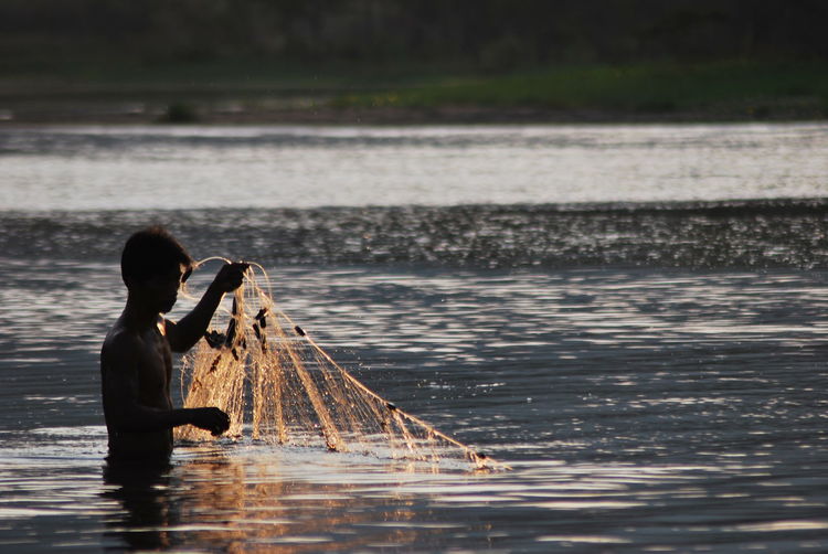 Shirtless fisherman fishing in lake