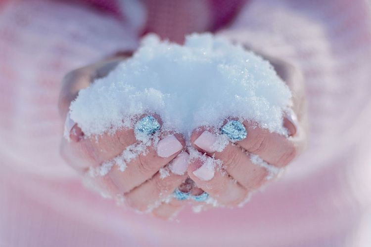 Close-up of manicured hands holding snow