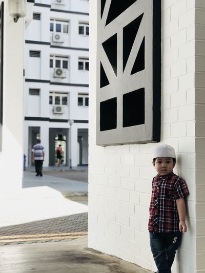Portrait of boy standing against built structure