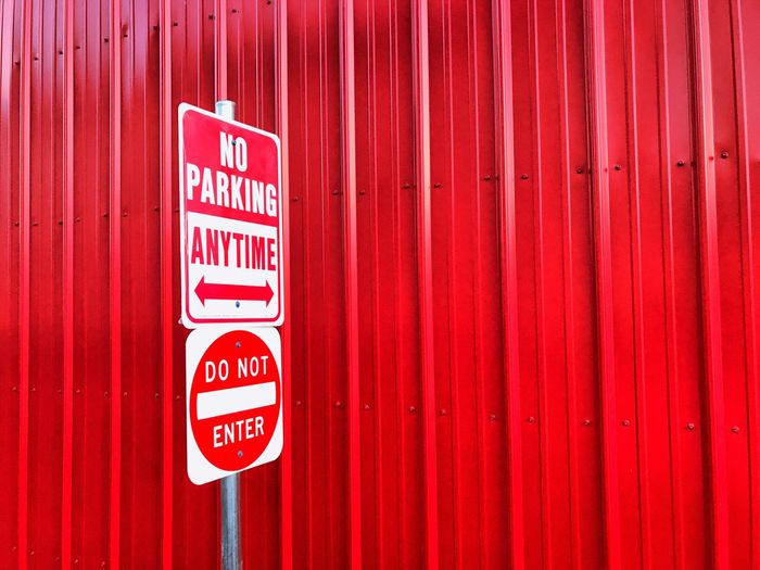 Close-up of no parking sign on red wall