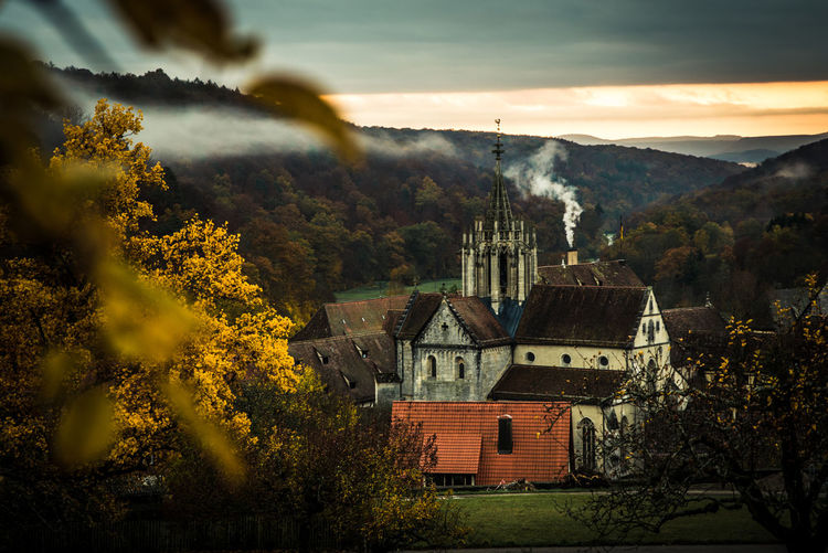 Historic church and village against sky during sunrise