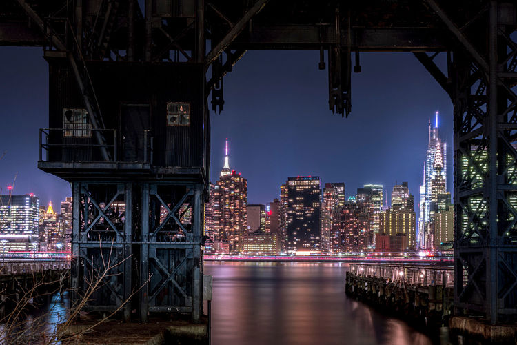 Old railway crane over east river in queens, new york at night
