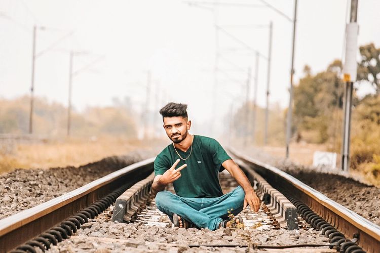 Young man sitting on railroad track