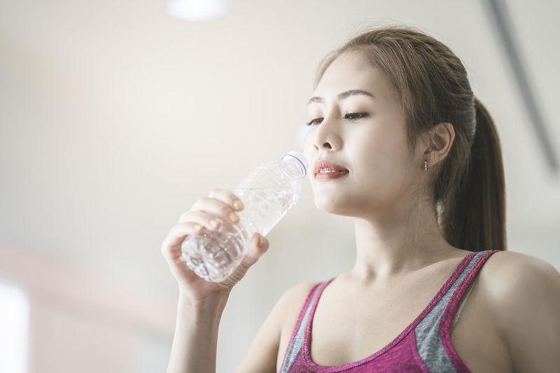 Portrait of beautiful woman drinking water from bottle