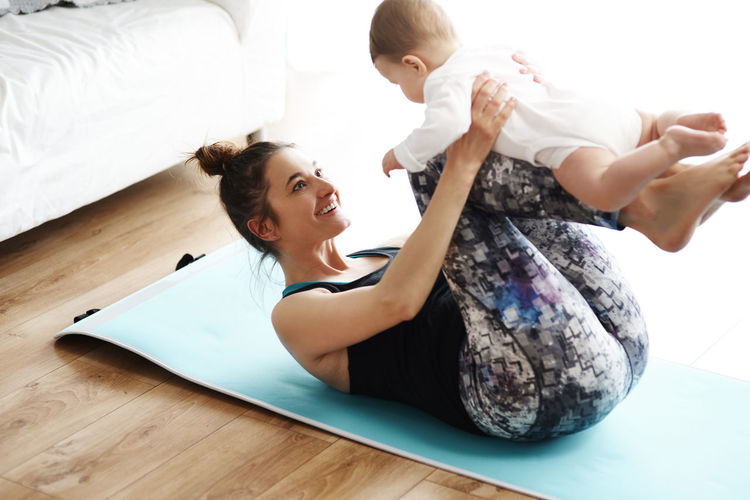 Mother and baby exercising on yoga mat at home