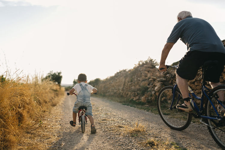 Back view of little boy and his great-grandfather on bicycle tour