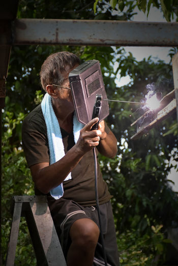 The welder welding steel structure use only welding mask for protection intense light without ppe.