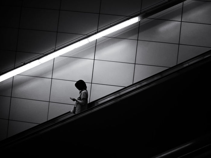 Side view of woman standing on escalator