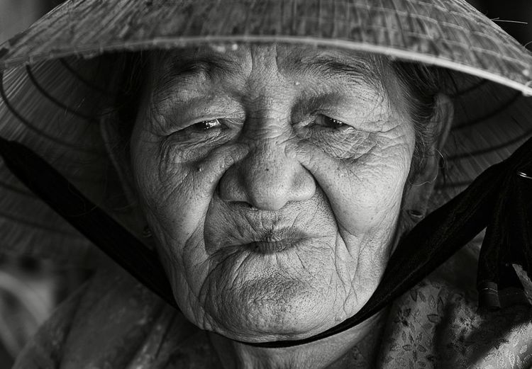 Close-up portrait of senior woman wearing asian style conical hat