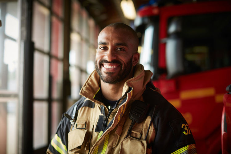 Portrait of smiling male firefighter in uniform at fire station