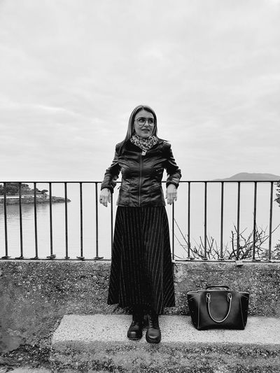 Portrait of woman standing against railing