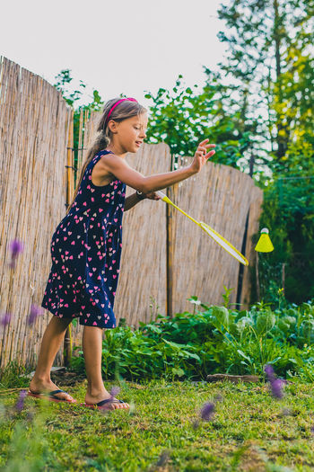 Full length of girl playing badminton at yard