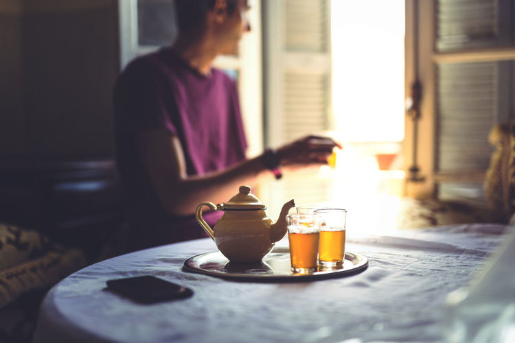 Teapot and drinks on table with man sitting in background