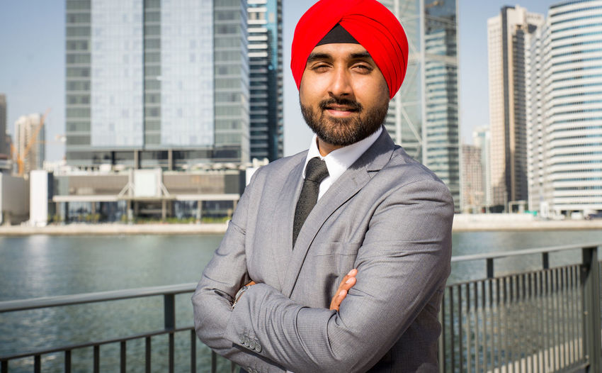 Portrait of businessman wearing turban standing against river