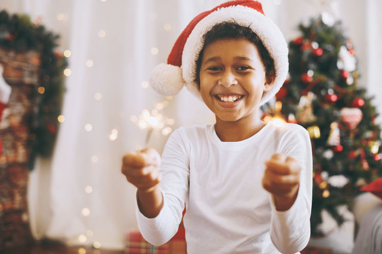 Portrait of smiling young woman holding christmas tree