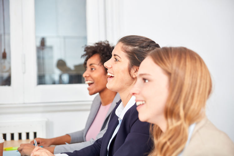 Profile view of smiling businesswomen sitting at office