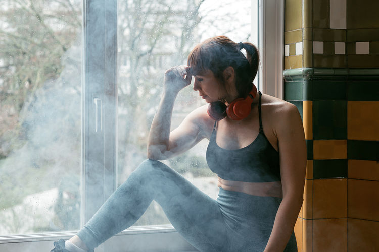Sport woman resting after workout session while wearing headphones - focus on face