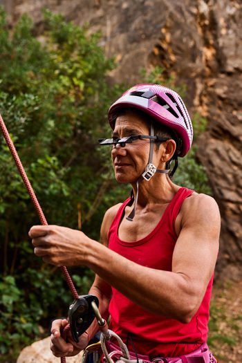 Active senior woman wearing prism glasses while holding climbing rope