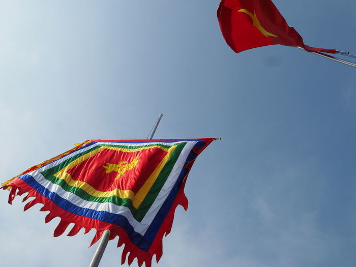 Low angle view of flags outside ngoc son temple against blue sky
