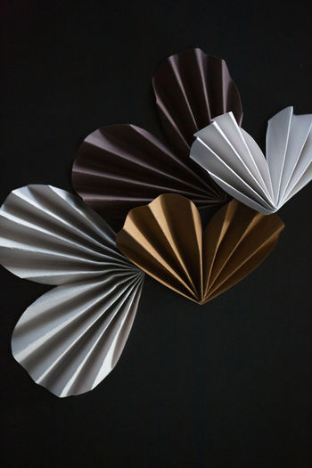 Close-up of neutral colored paper origami hearts on dark background