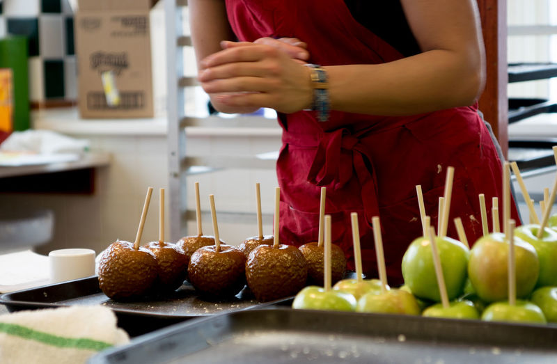 Midsection of woman preparing taffy apples in kitchen