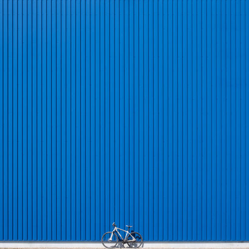 Bicycle parked against blue corrugated iron