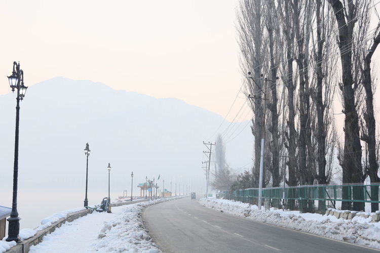 Road by snow covered mountain against sky, srinagar kashmir 