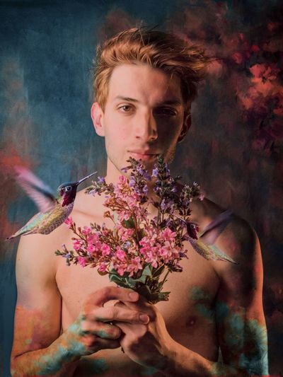 Portrait of young man holding flower