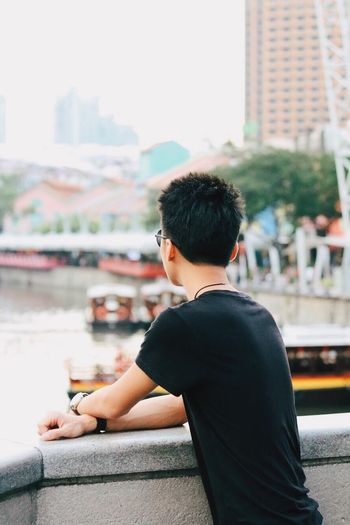 Rear view of young man leaning on railing at clarke quay