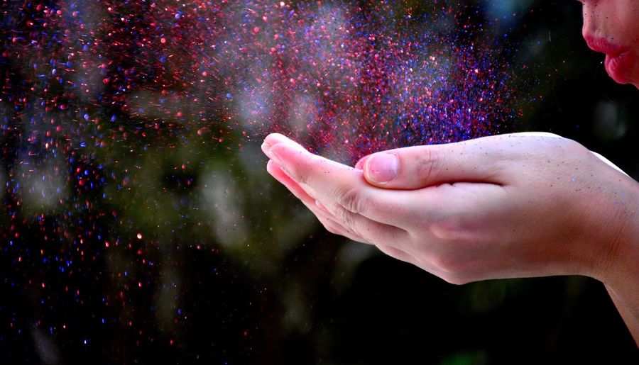 Woman blowing glitter outdoors