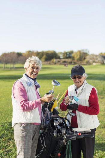 Happy senior women with clubs on golf course