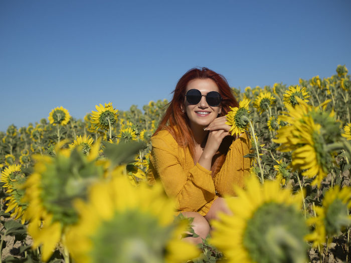 Portrait of woman wearing sunglasses while standing against yellow flower