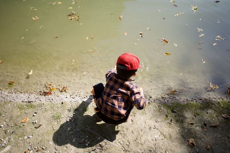 A boy playing water by a lake