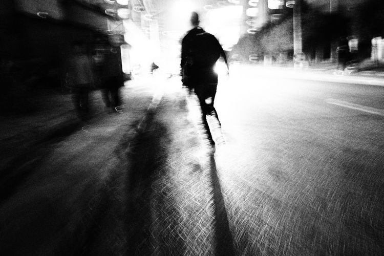 Silhouette man walking on road in city