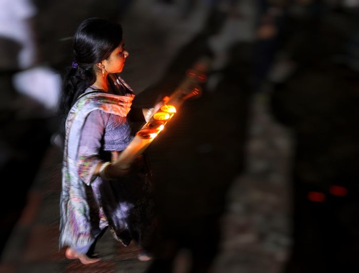 Women walking with dia-oil lamp on hand at rakher upobash inside crowd