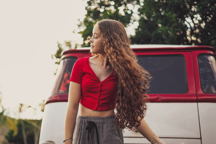 Cheerful teenager girl looking away while standing by van