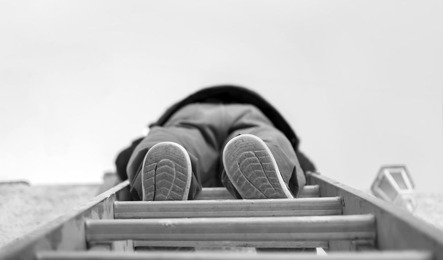 Low section of person on ladder against sky