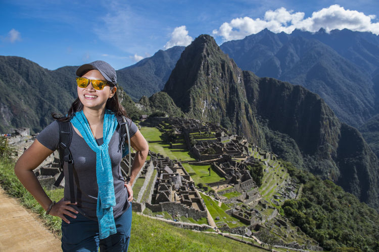 Woman at inca ruins looking at camera smiling, machu picchu, peru